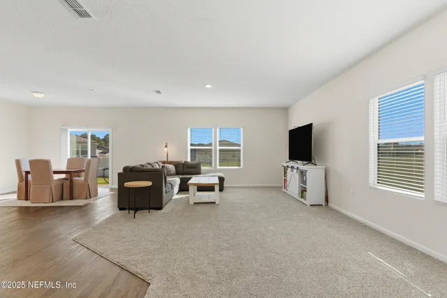 a living room with furniture a flat screen tv and kitchen view