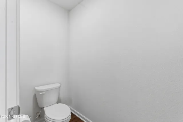 a white toilet sitting next to a white wall