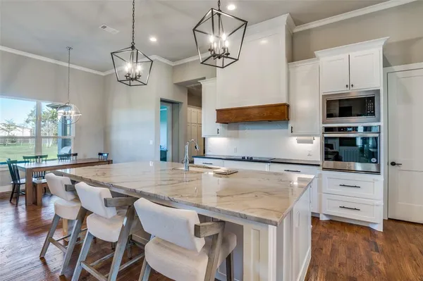 a kitchen with granite countertop a table chairs stainless steel appliances and wooden floor