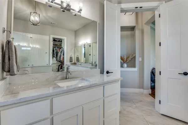 a bathroom with double vanity sinks a vanity a lamp and a mirror