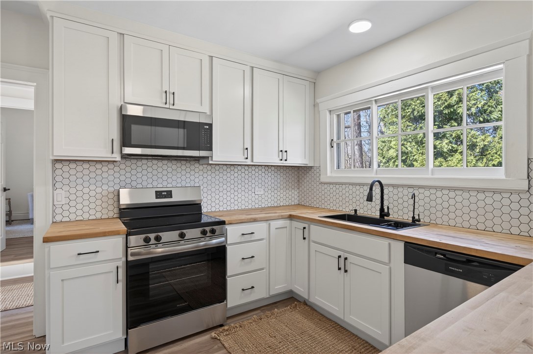 14939 Caves Road Novelty, OH 44072 - Photo 12 of 42 Kitchen featuring butcher block counters, stainless steel appliances, white cabinets, and backsplash