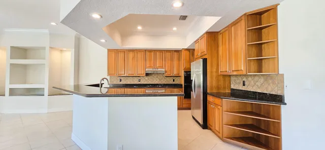 a kitchen with stainless steel appliances granite countertop a refrigerator a stove and a sink
