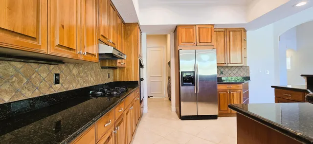 a kitchen with granite countertop wooden cabinets and a refrigerator