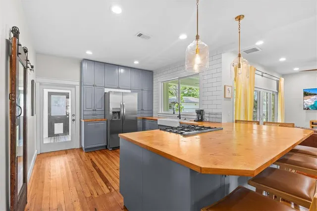 a kitchen with stainless steel appliances a dining table chairs stove refrigerator and microwave