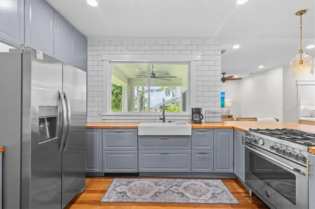 a kitchen with stainless steel appliances granite countertop a refrigerator a sink a stove and a window