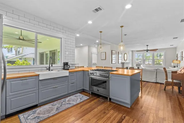 a large kitchen with stainless steel appliances granite countertop a large kitchen island a stove a sink a dining table and chairs