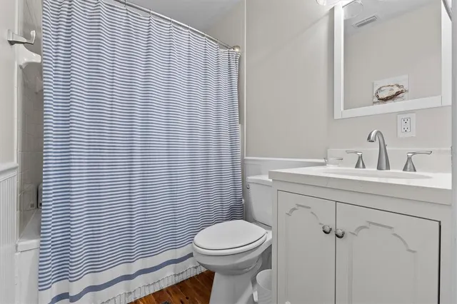 a bathroom with a toilet a sink a mirror and shower curtain