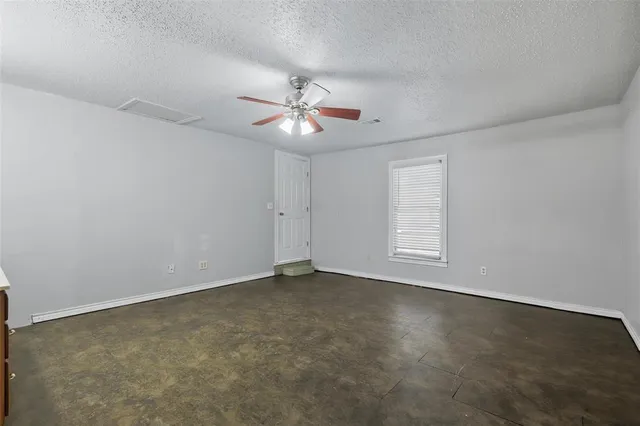 an empty room with chandelier fan and windows