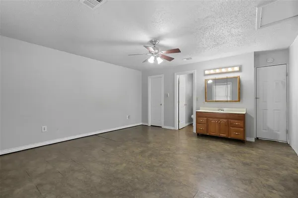 an empty room with a fireplace and chandelier fan
