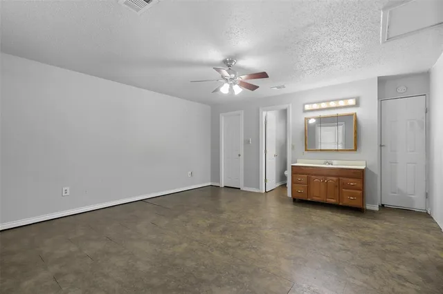 an empty room with a fireplace and chandelier fan