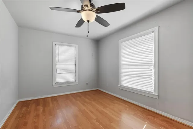 an empty room with windows and fan