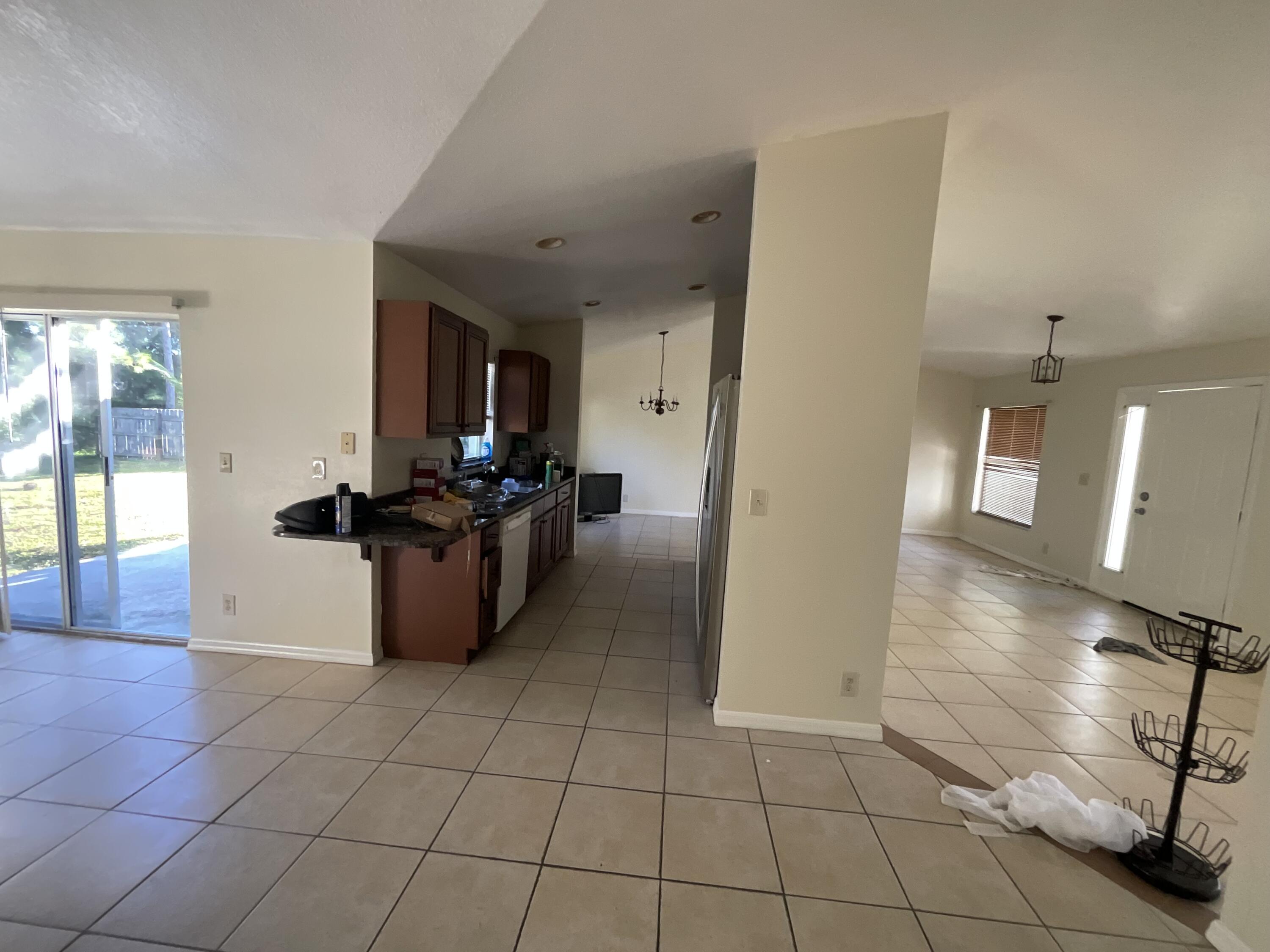 1931 Southwest Fears Avenue Port St. Lucie, FL 34953 - Photo 9 of 13 a kitchen with granite countertop a stove a sink and a refrigerator