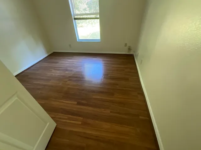 an empty room with wooden floor and windows