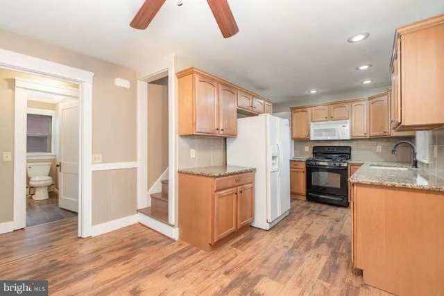 a kitchen with granite countertop a refrigerator stove top oven and sink