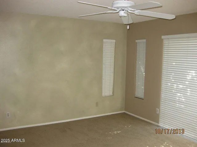 an empty room with a window and a fan