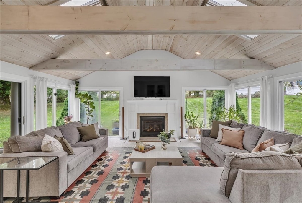 1057 Whitman Street Hanson, MA 02341 - Photo 26 of 40 a living room with furniture a fireplace and a flat screen tv
