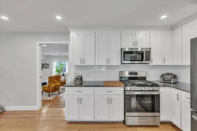 a kitchen with stainless steel appliances granite countertop a stove a sink and a white cabinets
