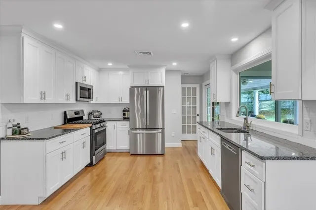 a kitchen with granite countertop a sink stainless steel appliances and window