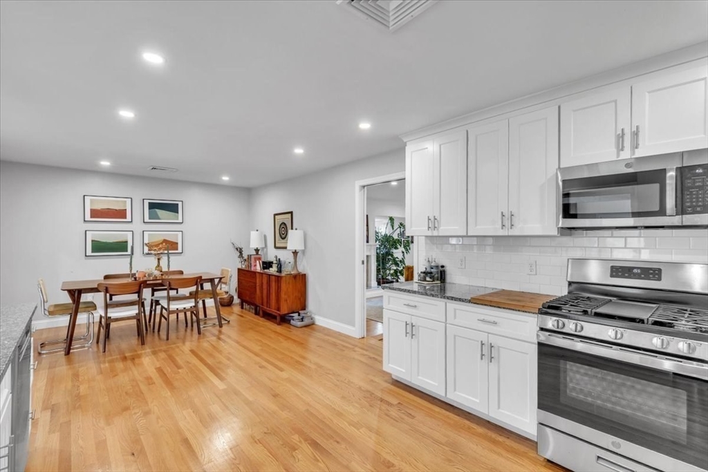 1057 Whitman Street Hanson, MA 02341 - Photo 7 of 40 a kitchen with stainless steel appliances granite countertop a stove top oven a sink a dining table and chairs with wooden floor