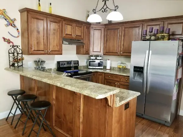 a kitchen with stainless steel appliances granite countertop a refrigerator a sink dishwasher a stove with wooden cabinets and floor