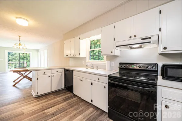 a large white kitchen with kitchen island a sink stainless steel appliances and cabinets