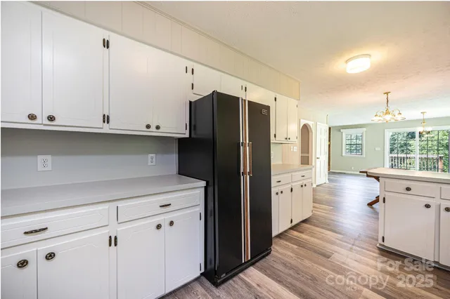 a kitchen with granite countertop white cabinets appliances a sink and a window