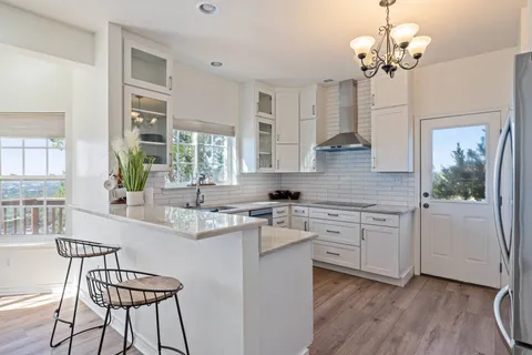 a kitchen with stainless steel appliances granite countertop a stove a sink dishwasher a dining table and chairs with wooden floor