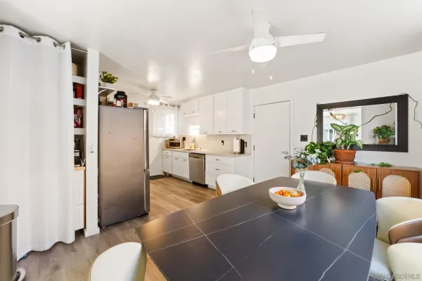 a kitchen with stainless steel appliances a refrigerator a sink a dining table and chairs with wooden floor