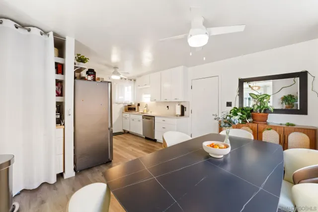 a kitchen with stainless steel appliances a refrigerator a sink a dining table and chairs with wooden floor