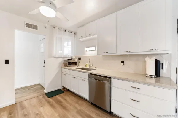 a kitchen with granite countertop white cabinets white stainless steel appliances and sink