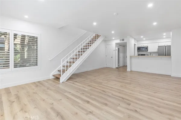 a view of an empty room with wooden floor and stairs