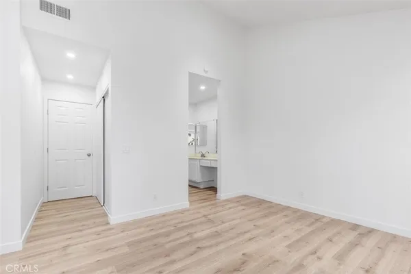 a view of empty room with wooden floor and kitchen