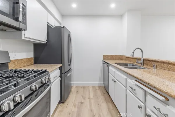 a kitchen with granite countertop a sink stove and refrigerator
