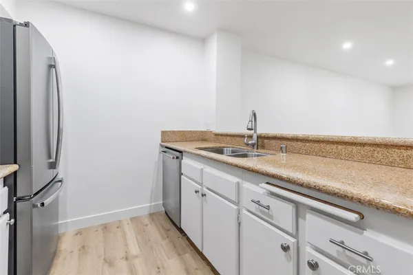 a kitchen with granite countertop a sink and a white cabinets