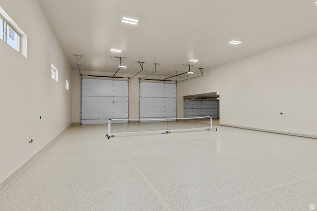 2955 East Rimrunner Drive St. George, UT 84790 - Photo 17 of 35 Spacious multi-car garage featuring a light-colored epoxy floor coating, multiple overhead garage doors, recessed ceiling lighting, and high ceilings