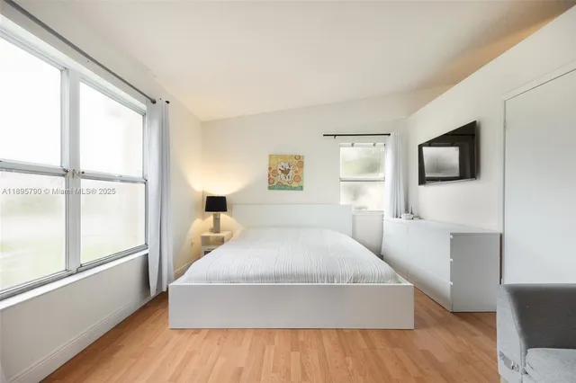 a bedroom with a large bed and a flat tv screen on dresser