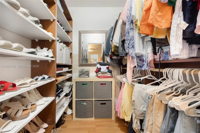 a view of walk in closet with clothes and shoes