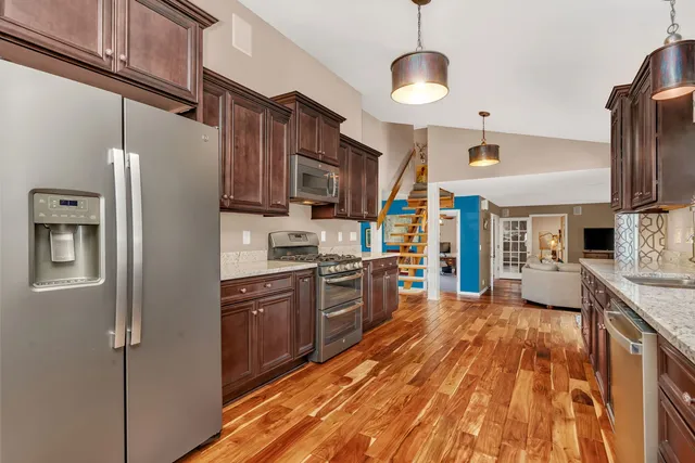 a large kitchen with stainless steel appliances granite countertop a refrigerator a stove and a wooden floors