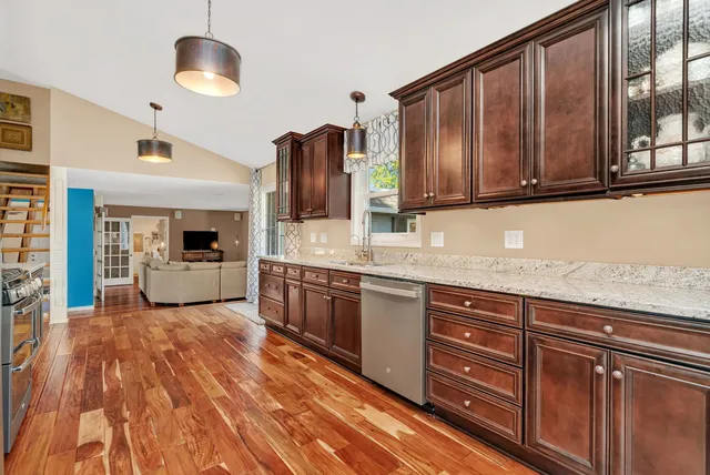 a kitchen with granite countertop a sink cabinets and stainless steel appliances