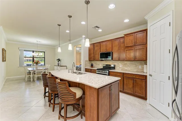 a kitchen with stainless steel appliances granite countertop a stove top oven a sink refrigerator and cabinets