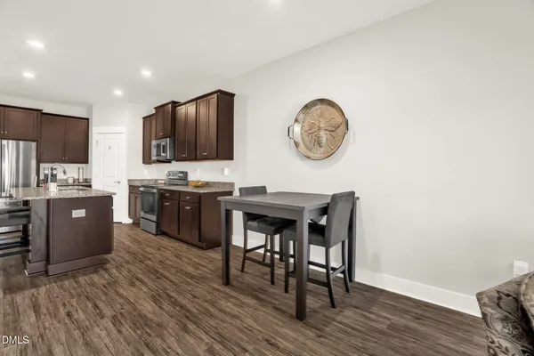 a kitchen with a table chairs a stove a refrigerator and a dining table