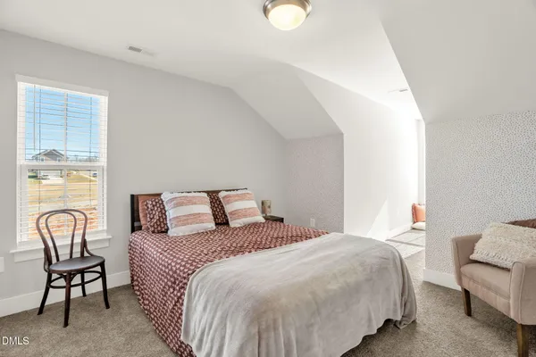 a bedroom with a bed chair and window