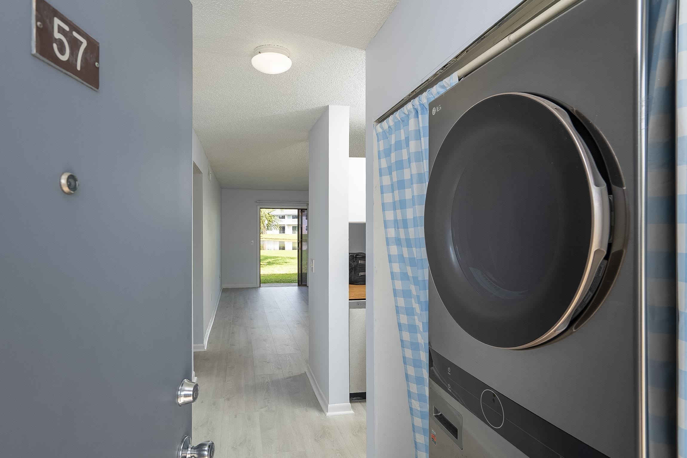 700 West Pope Road, Unit H57 St. Augustine, FL 32080 - Photo 25 of 52 Laundry room with stacked washing machine and dryer, a textured ceiling, and light wood finished floors