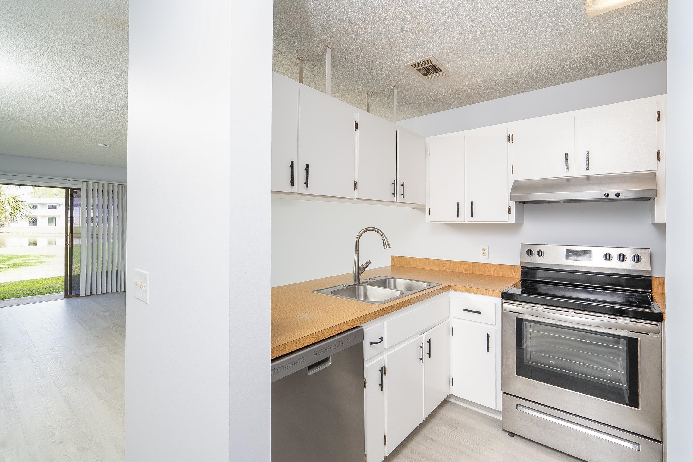 700 West Pope Road, Unit H57 St. Augustine, FL 32080 - Photo 6 of 52 Kitchen featuring a textured ceiling, stainless steel appliances, light countertops, white cabinetry, and light wood finished floors
