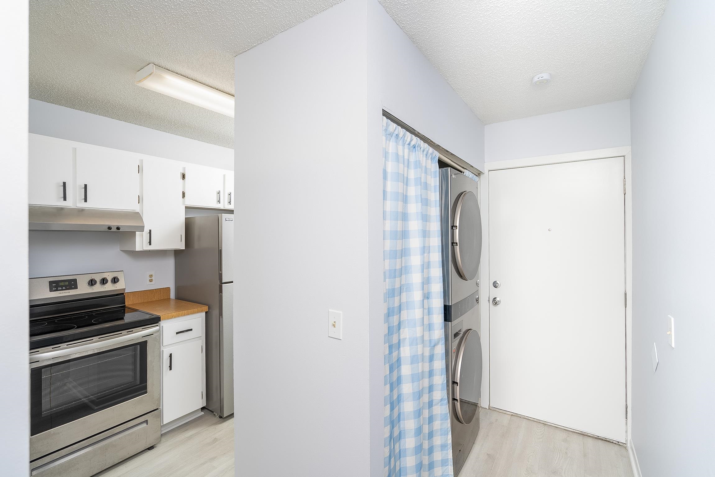 700 West Pope Road, Unit H57 St. Augustine, FL 32080 - Photo 7 of 52 Laundry area with a textured ceiling, light wood-type flooring, and stacked washing machine and dryer