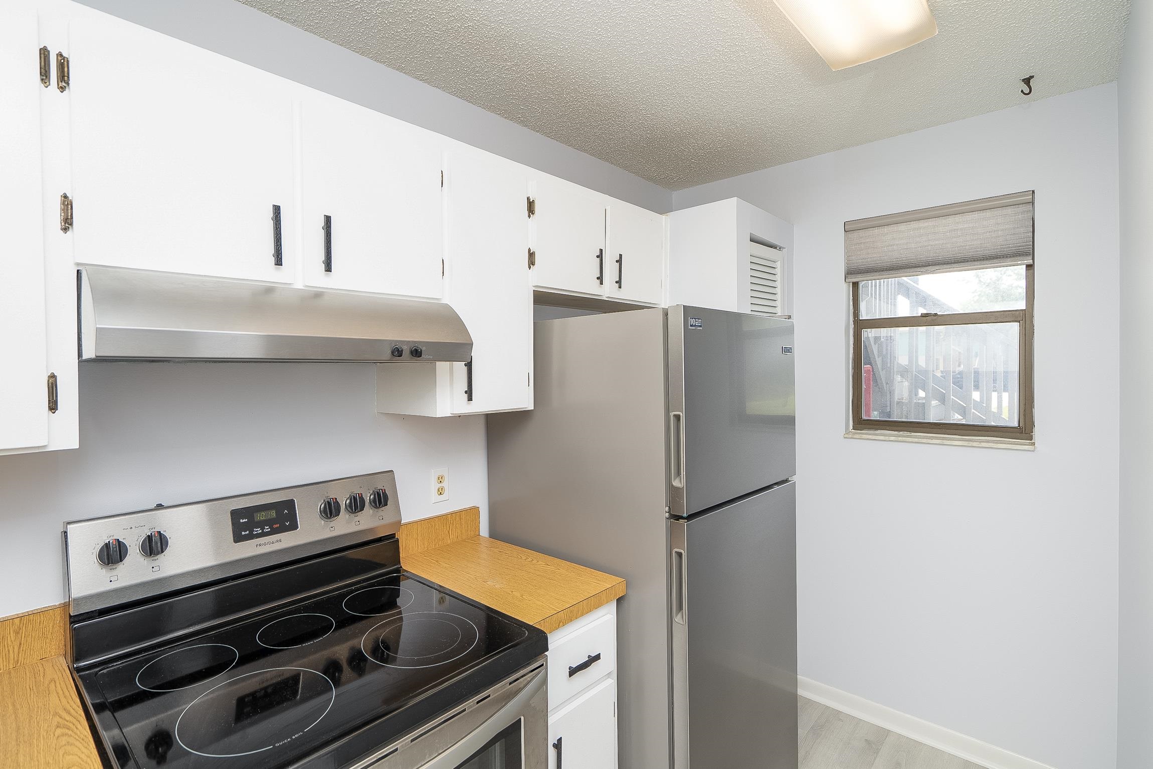 700 West Pope Road, Unit H57 St. Augustine, FL 32080 - Photo 9 of 52 Kitchen with electric stove, light countertops, white cabinetry, a textured ceiling, and light wood-type flooring