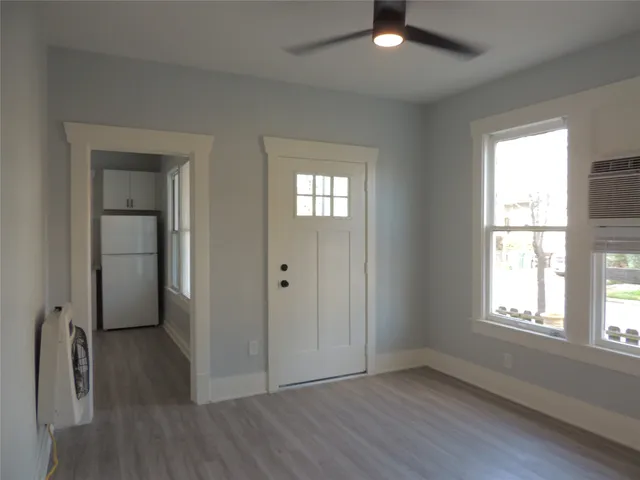 an empty room with wooden floor cabinet and windows