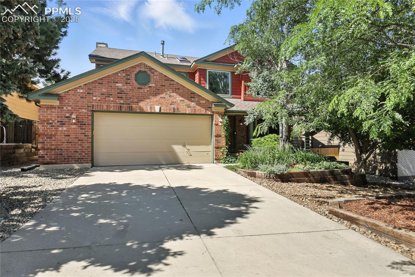 2130 Wickes Road Colorado Springs, CO 80919 - Photo 1 of 49 View of front of home with driveway, an attached garage, brick siding, and roof mounted solar panels