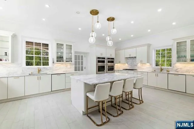 a kitchen with stainless steel appliances kitchen island granite countertop a table chairs sink and cabinets