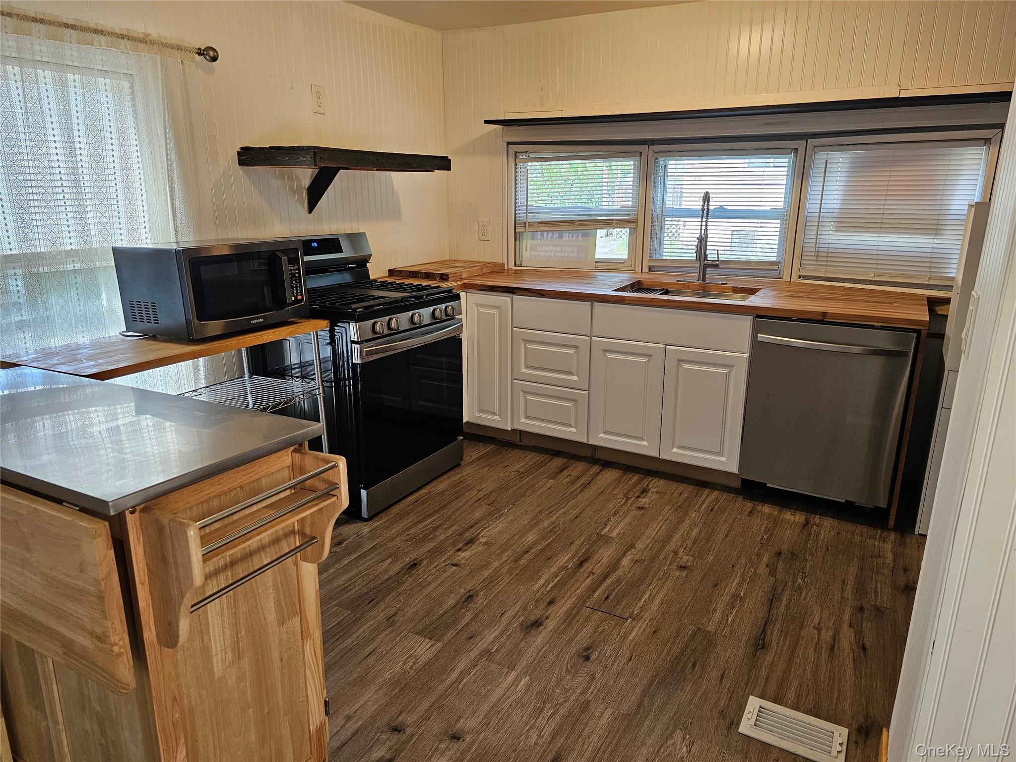 1964-106 River Road, Unit 106 Calverton, NY 11933 - Photo 2 of 26 a kitchen with stainless steel appliances granite countertop a stove a sink and a microwave